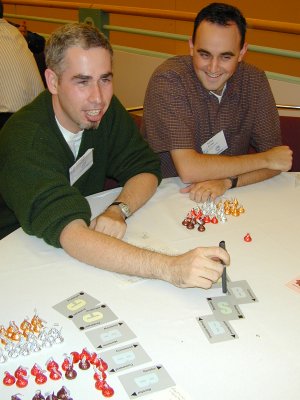 two people sitting at a round table with cards and candy
