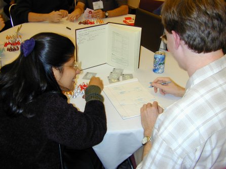 two people sitting at a round table with cards and candy behind a book